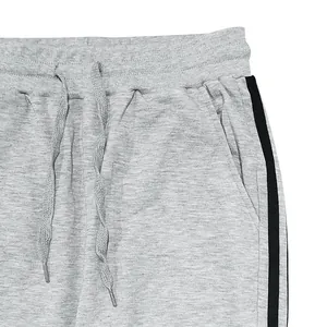 Close-up detail of grey men's joggers showing drawstring and black side stripes.