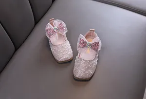 Detailed view of pink princess shoes featuring pearls and sequin bows for girls.