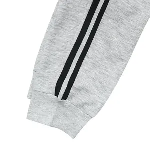 Detailed macro view of ribbed ankle cuff and black side stripes on men's grey sports joggers