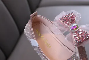 Close-up detail of pink sparkling girls princess shoes with a rhinestone bow and pearls