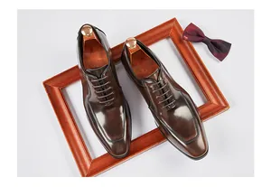 Macro view of polished brown leather men's formal shoes displayed with a bow tie.