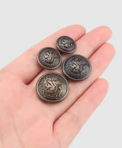 Detailed view of antique brass metal buttons with lion crest on a hand for scale.