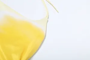 Close-up detail of the yellow and white gradient fabric on a stylish halter neck dress