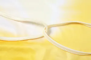 Close-up detail of yellow tie-dye halter dress showing high-quality strap stitching