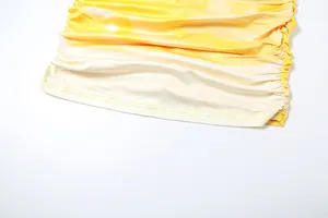 Macro detail of the yellow and white gradient ruched hemline on a summer bodycon dress