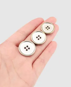Gros plan de trois boutons en laiton japonais de haute qualité à quatre trous dans une main.