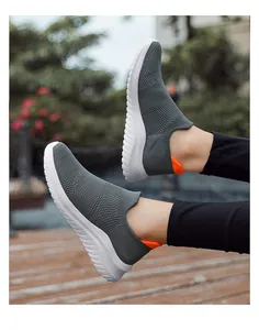 Close-up of grey flyknit sock shoes with white wavy soles worn on an outdoor wooden deck