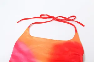 Close-up of vibrant pink and orange ombre halter neck dress with red tie-up strap