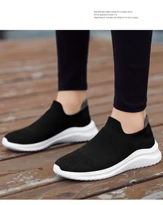 Close-up detail of black fly-knit slip-on sock sneakers featuring durable white soles.