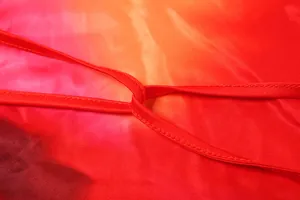Detail shot of gradient color-clash dress fabric with fine stitching on straps.