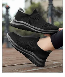 Close-up of black breathable flyknit slip-on sneakers with grey soles in outdoor setting