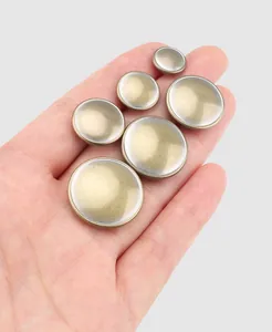 Macro view of high-end dome shaped brass metal buttons held in a hand for the scale