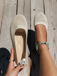 Detail view of breathable beige knit round toe flat shoes for women on wooden deck
