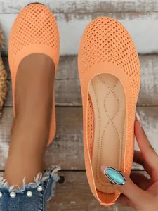 Close-up of orange mesh fly-knit flat shoes with a comfortable round toe design