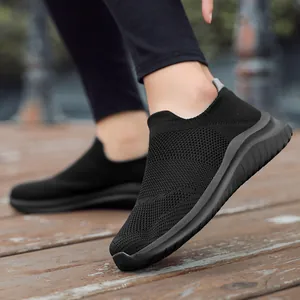 Comfortable black fly-knit slip-on walking shoes for adults on wooden deck