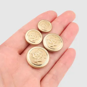 Four gold brass blazer buttons with heraldic emblem held in a hand for scale