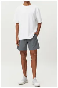Male model wearing white crewneck cotton t-shirt with grey sports shorts in studio
