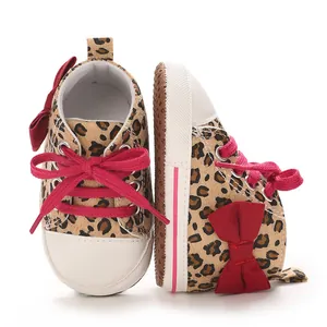 Detailansicht von Baby-Sneakern mit Leopardenmuster, roter Schleife und roten Schnürsenkeln