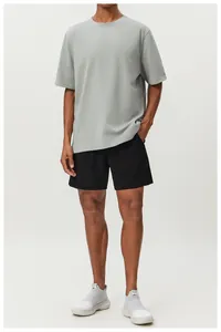 Full view of a man wearing a grey breathable cotton athletic T-shirt and black sports shorts