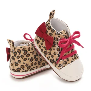 Detailansicht der Babyschuhe mit Leopardenmuster, roter Schleife und rosa Schnürsenkeln