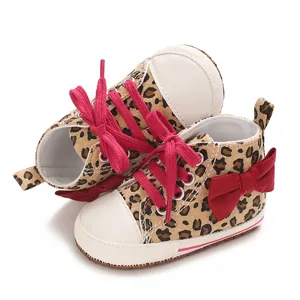 Detailansicht von Baby-Sneakern mit Leopardenmuster, roter Schleife und Schnürsenkeln.