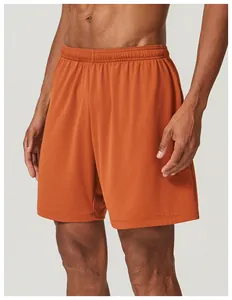 Detailed close-up of orange breathable mesh sports shorts worn by a male athlete