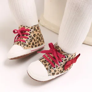 Nahaufnahme von stilvollen Baby-Sneakern mit Leopardenmuster, roter Schleife und weicher Sohle