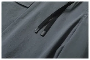 Gros plan détaillé d'un pantalon cargo gris foncé avec tissu texturé et cordon de serrage