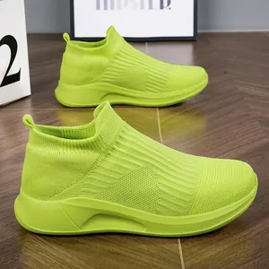 Λεπτομερής προβολή νέον πράσινων πλεκτών sneakers με ραβδωτή υφή σε ξύλινο δάπεδο
