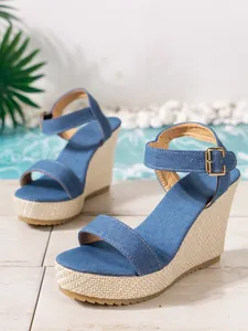 Dettaglio sandali con zeppa in denim blu con plateau intrecciato e cinturino