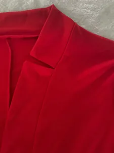 Close-up detail of the professional notched lapel on a vibrant red women's blazer jacket.