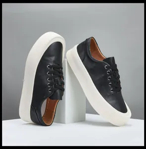 Détail de baskets en cuir noir pour hommes avec semelles compensées blanches épaisses.