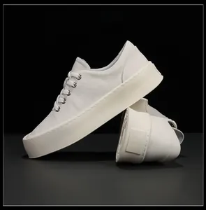 Vue latérale détaillée de baskets minimalistes en cuir blanc à semelles compensées.