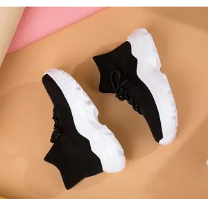 Top view of black knit high-top sneakers with thick white soles for casual sport.
