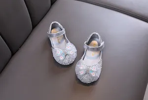 Nahaufnahme von silbernen Glitzerprinzessinnenschuhen für Mädchen mit Spitzenschleife und Blumen