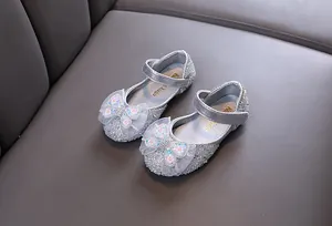 Nahaufnahme von silbernen Mädchen-Prinzessin-Schuhen mit Strass und Spitzenbogen.