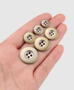 Vue détaillée de divers boutons métalliques à quatre trous en bronze et argent pour vêtements.