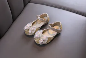 Nahaufnahme goldener Glitzer-Prinzessinnenschuhe für Mädchen mit Strass-Schleifen