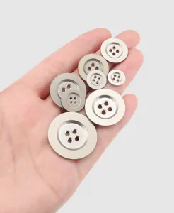 Close-up view of premium assorted metal four-hole buttons held in hand for scale