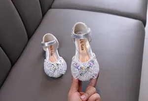 Detailansicht silberner Prinzessinnenschuhe mit Strass-Schmetterling und Perlen.