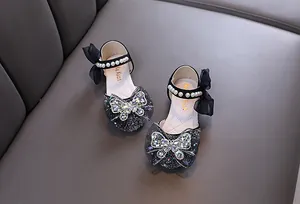 Detalle de zapatos de princesa negros para niña con mariposa de pedrería y perlas
