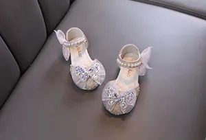 Detalle de zapatos de princesa para niñas con pedrería, perlas y lazos de tul
