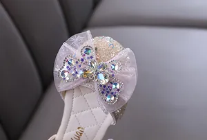 Detalle de un lazo de malla rosa con una mariposa de pedrería en un zapato de princesa para niña