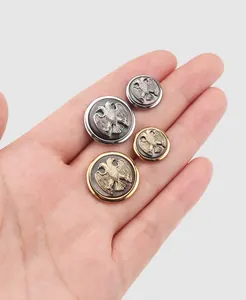Nahaufnahme hochwertiger Metallknöpfe mit aufwendigem Adler-Emblem auf dunkler Einlage