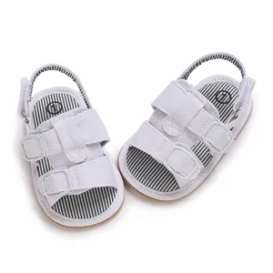 Nahaufnahme weißer Baby-Leinensandalen mit gestreifter Innensohle und Schnallenverschluss.