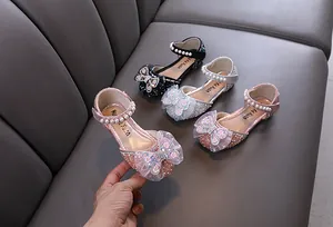Detail view of sparkling girls' princess shoes with rhinestone butterfly bows and pearl straps