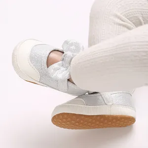 Close-up of silver baby walking shoes with soft anti-slip dotted sole and bow detail