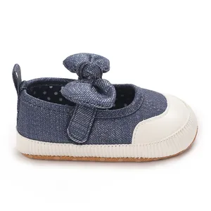 Close-up view of blue denim baby girl walking shoes featuring a large decorative bow.