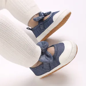 Close-up detail of infant baby girl denim pre-walking shoes with sparkling bow decoration