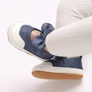 Close-up of denim baby shoes with a large bow and non-slip rubber soles for toddlers.